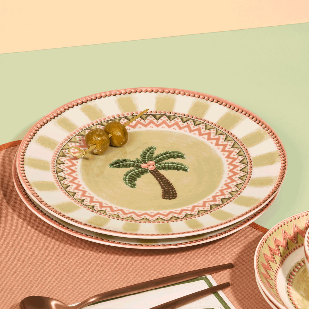 A Tale in Beads dessert plate stacked on a dinner plate with olives