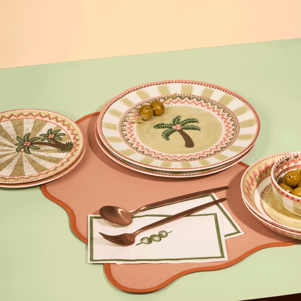 A Tale in Beads place setting styled on a coral mat against sage green