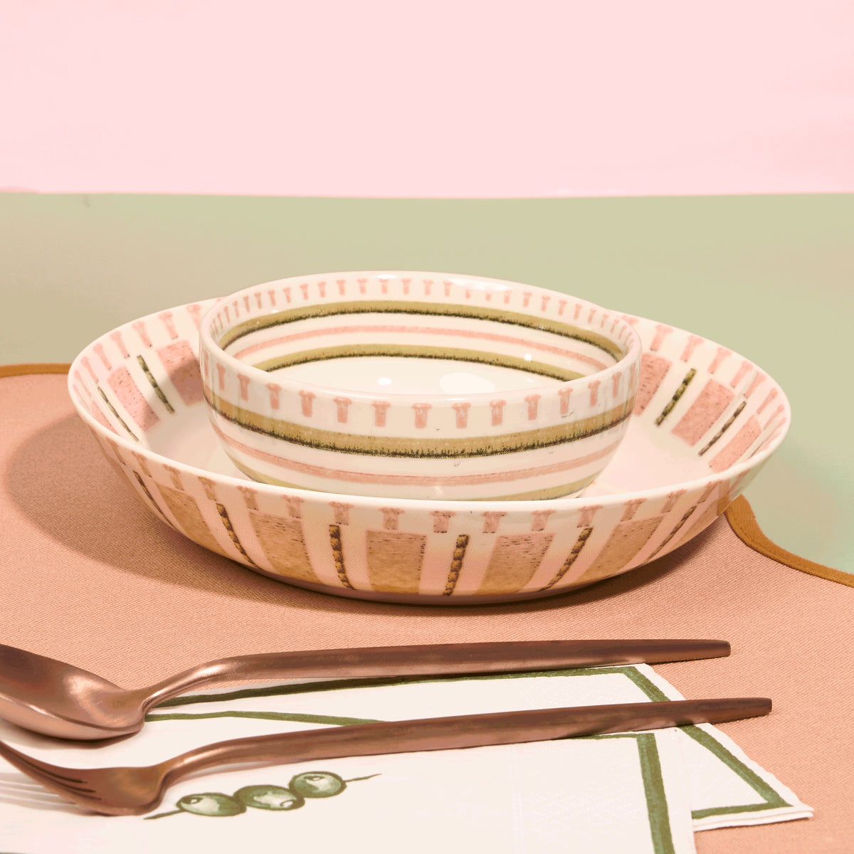 Stitches of the Wild soup bowl resting in a coral and olive striped salad plate